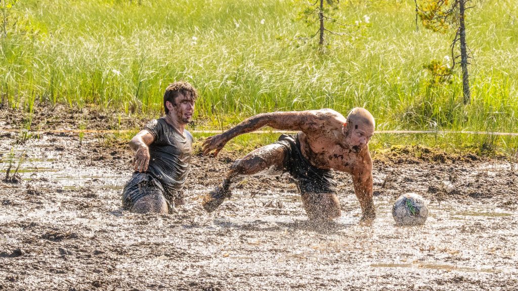 Kaksi miestä pelaavat jalkapalloa suolla. Kyseessä on Suopotkupallon MM-kisat 2025