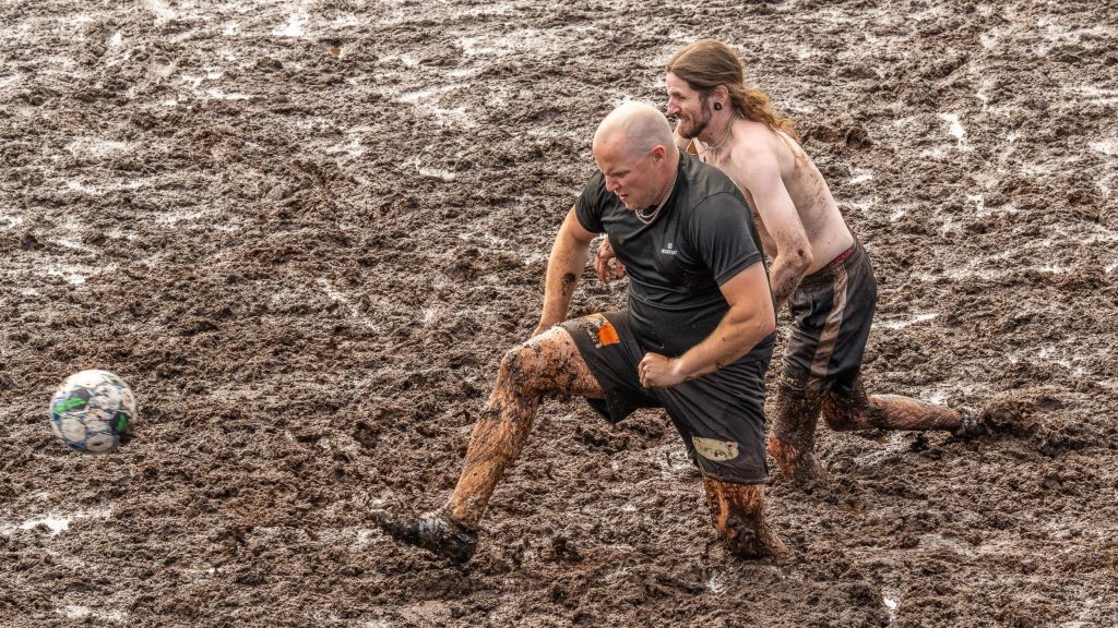 Kaksi miestä pelaavat jalkapalloa suolla. Kyseessä on Suopotkupallon MM-kisat 2025