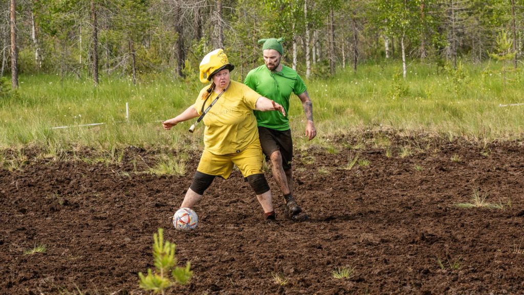 Mies ja nainen pelaavat jalkapalloa suolla. Kyseessä on Suopotkupallon MM-kisat 2025