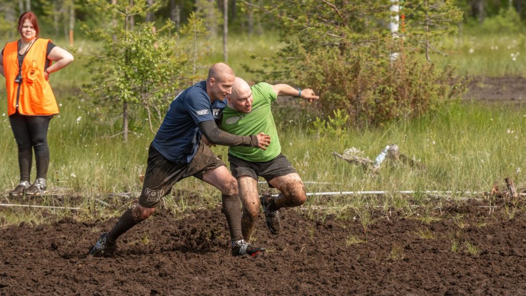 Kaksi miestä pelaavat jalkapalloa suolla. Kyseessä on Suopotkupallon MM-kisat 2025