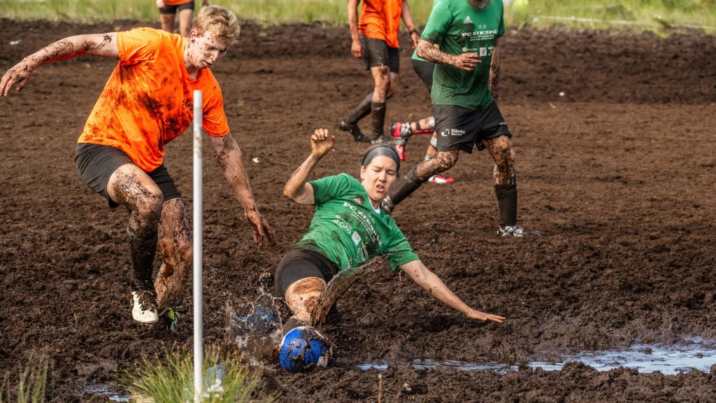 Miehistä ja naisista koostuvat joukkueet pelaavat jalkapalloa suolla. Kyseessä on Suopotkupallon MM-kisat 2025