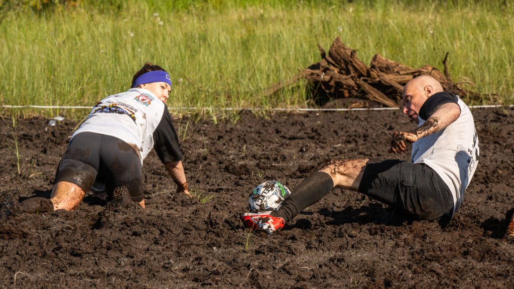 Miehistä ja naisista koostuvat joukkueet pelaavat jalkapalloa suolla. Kyseessä on Suopotkupallon MM-kilpailut vuonna 2025