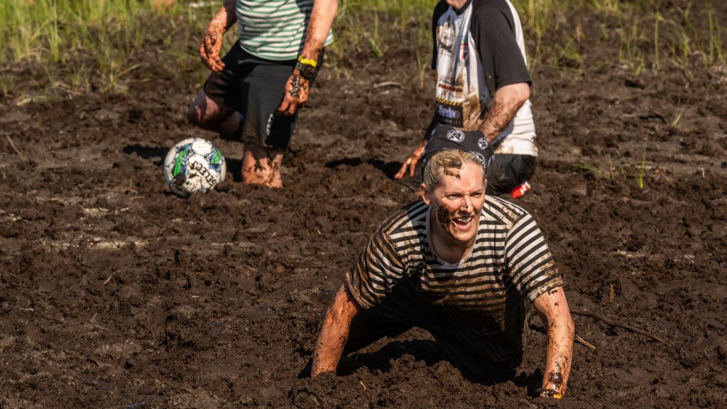 Nainen konttaa suolla. Kyseessä on Suopotkupallon MM-kilpailut vuonna 2025