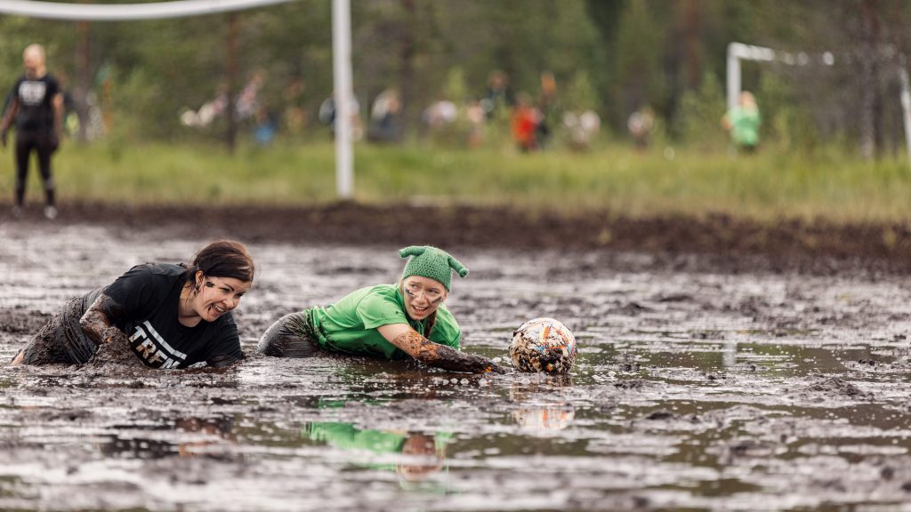 Kaksi naista ryömivät suolla pallon perässä. Kyseessä on Suopotkupallon MM-kisat 2024